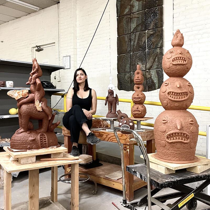 photo of Natalia Arbealez in a ceramic studio, surrounded by red clay sculptures 